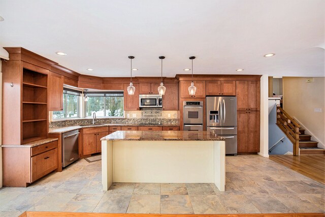 kitchen featuring a kitchen island, light stone countertops, appliances with stainless steel finishes, and decorative light fixtures