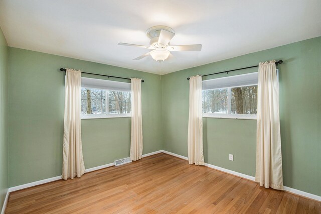 empty room featuring ceiling fan, a healthy amount of sunlight, and light hardwood / wood-style floors