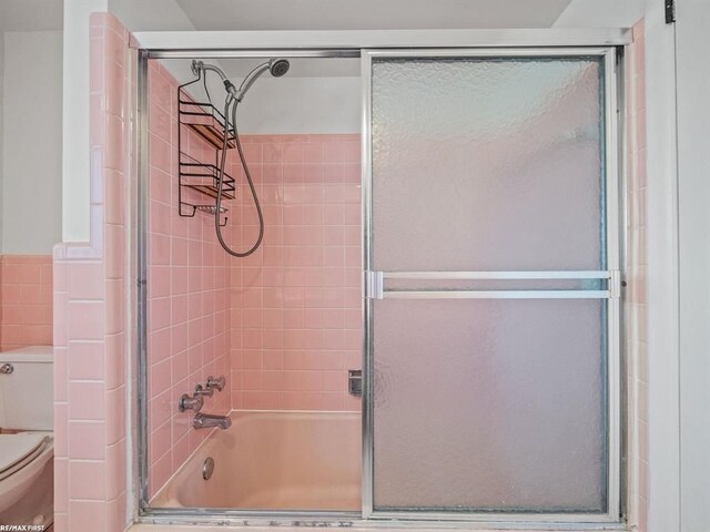 bathroom featuring shower / bath combination with glass door and toilet