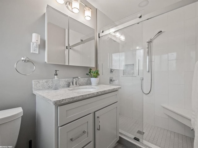 bathroom with vanity, toilet, and a shower with door