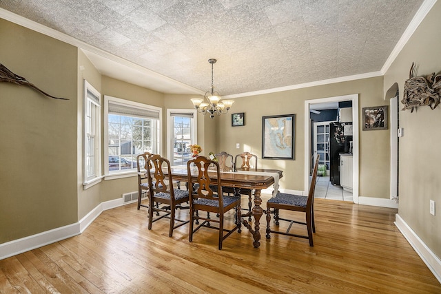 dining room with crown molding, a chandelier, and light hardwood / wood-style flooring