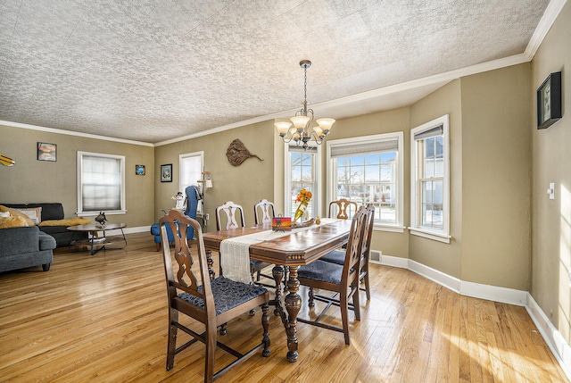 dining area with an inviting chandelier, crown molding, and light hardwood / wood-style floors