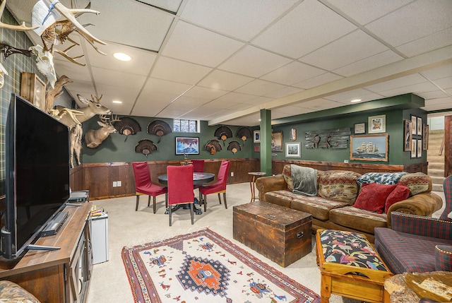 living room featuring a paneled ceiling and wooden walls