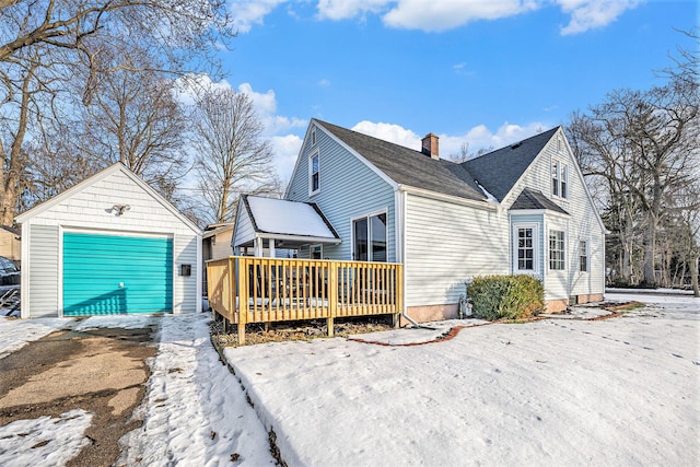 snow covered property featuring an outbuilding, a garage, and a deck