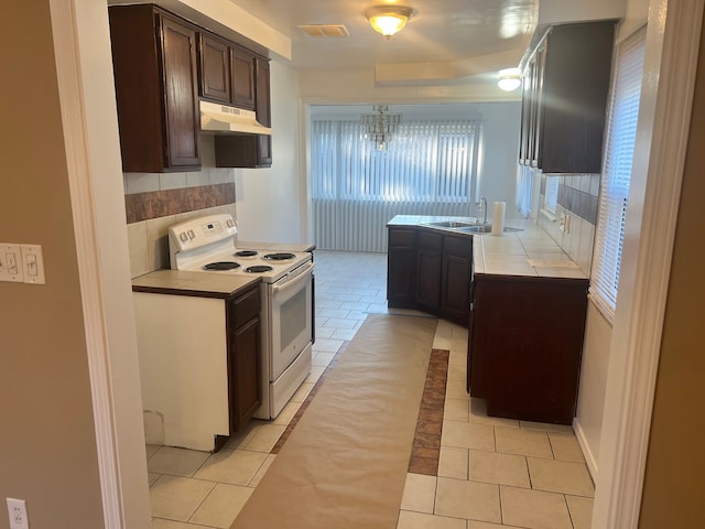 kitchen featuring electric stove, dark brown cabinetry, sink, and light tile patterned floors