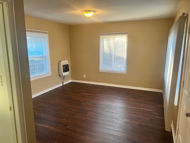 spare room featuring dark wood-type flooring and heating unit