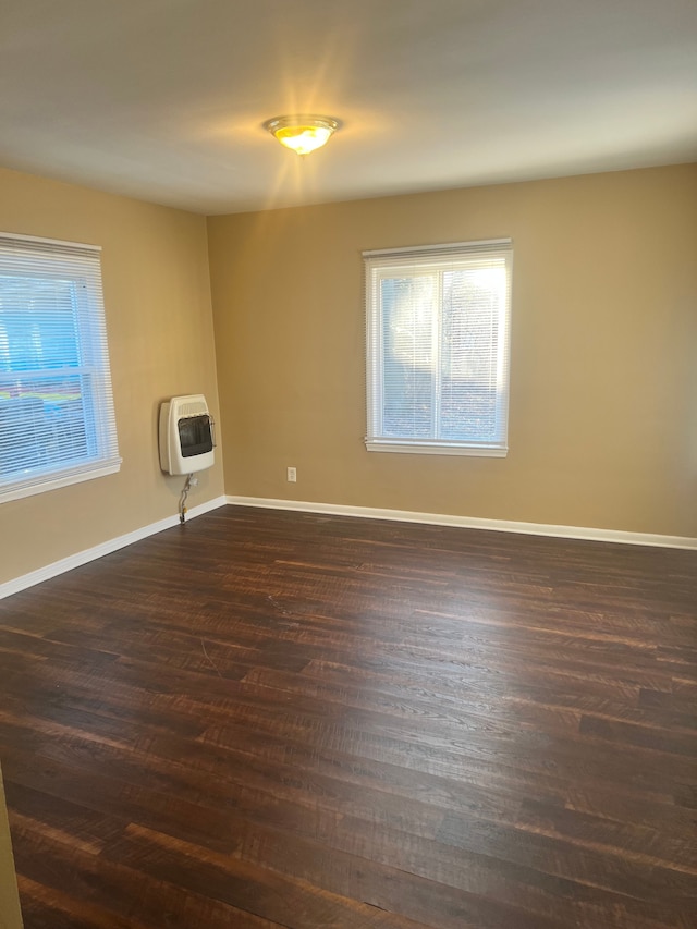 spare room with heating unit and dark hardwood / wood-style floors