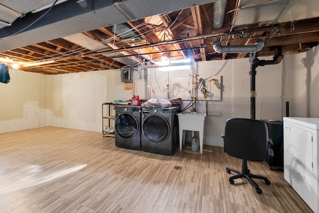 clothes washing area featuring hardwood / wood-style floors, sink, and washing machine and clothes dryer