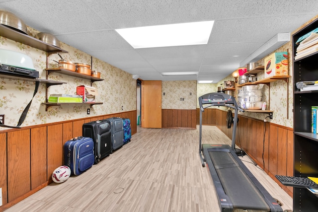 exercise area featuring a drop ceiling and light wood-type flooring