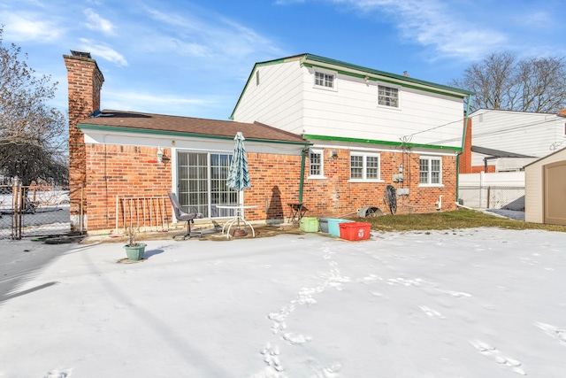 snow covered rear of property with a shed