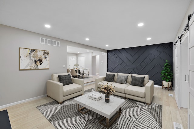 living room with a barn door and light wood-type flooring