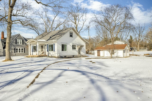 snow covered back of property with an outbuilding and a garage