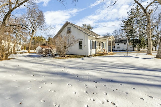 snow covered back of property with a porch