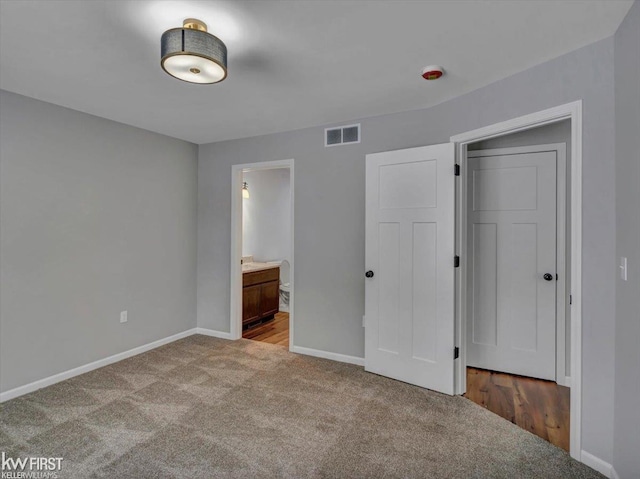 unfurnished bedroom featuring light carpet and connected bathroom