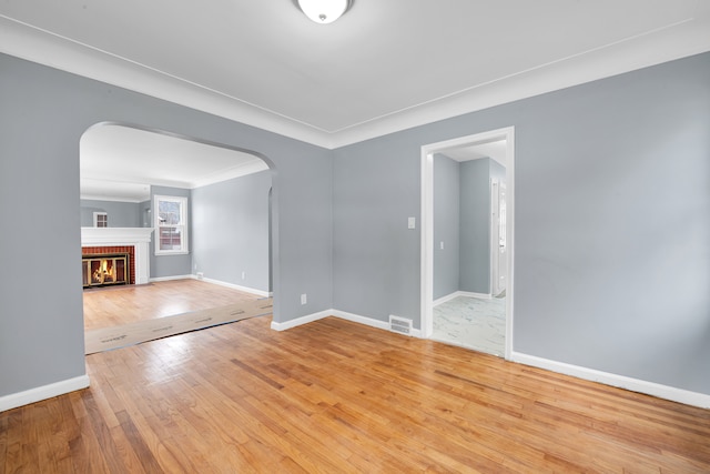 spare room with ornamental molding, wood-type flooring, and a fireplace