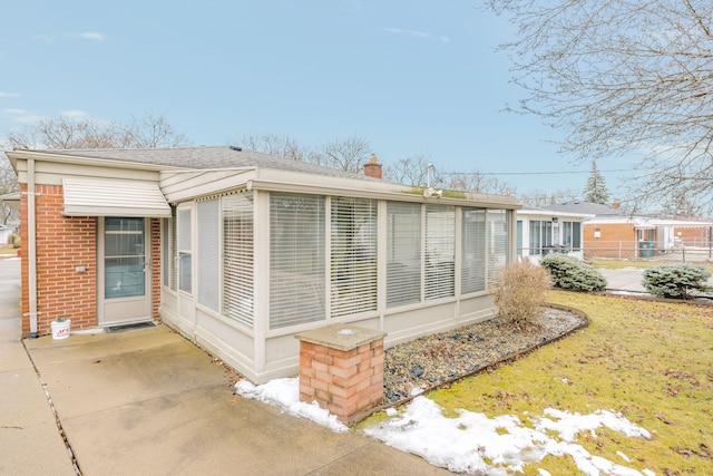 view of side of property featuring a sunroom and a lawn