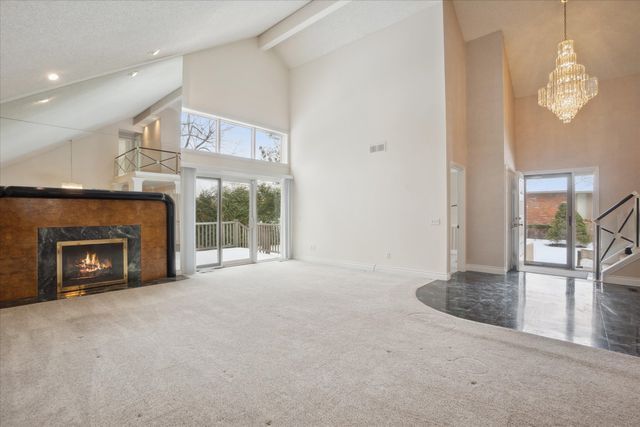 unfurnished living room featuring beam ceiling, plenty of natural light, carpet flooring, and a high end fireplace