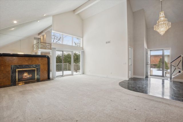 unfurnished living room featuring carpet floors, plenty of natural light, beam ceiling, and a high end fireplace