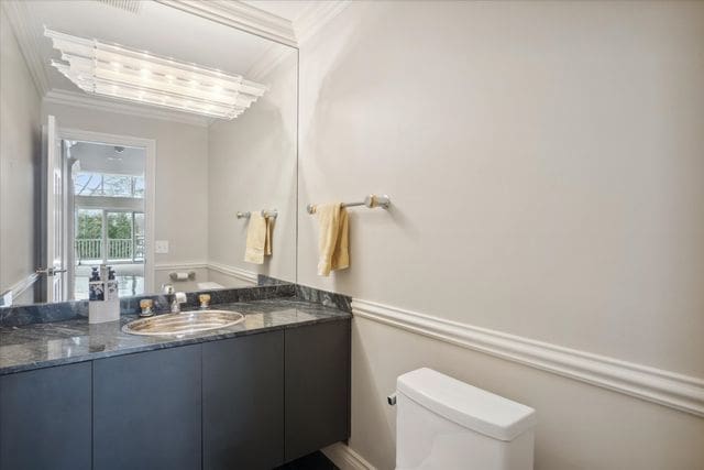 bathroom with ornamental molding, vanity, and toilet