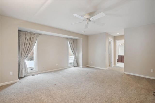 carpeted spare room featuring ceiling fan and a healthy amount of sunlight