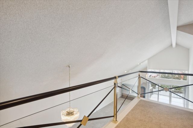 interior space featuring carpet floors, vaulted ceiling with beams, and a textured ceiling