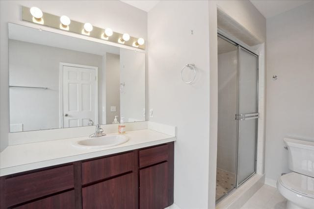 bathroom with vanity, a shower with shower door, and toilet