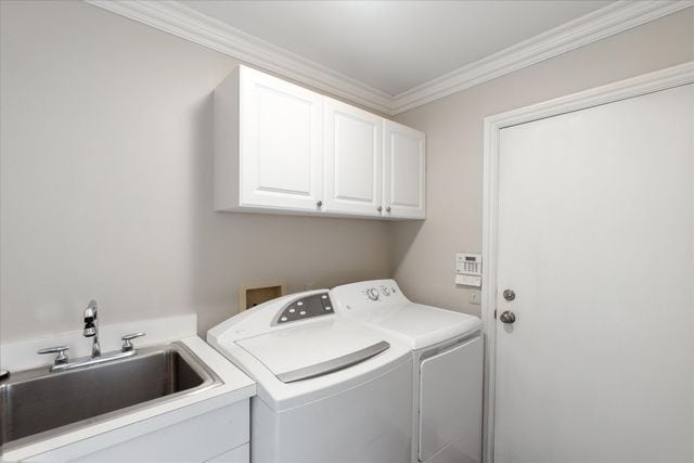 laundry area featuring crown molding, cabinets, sink, and washer and dryer