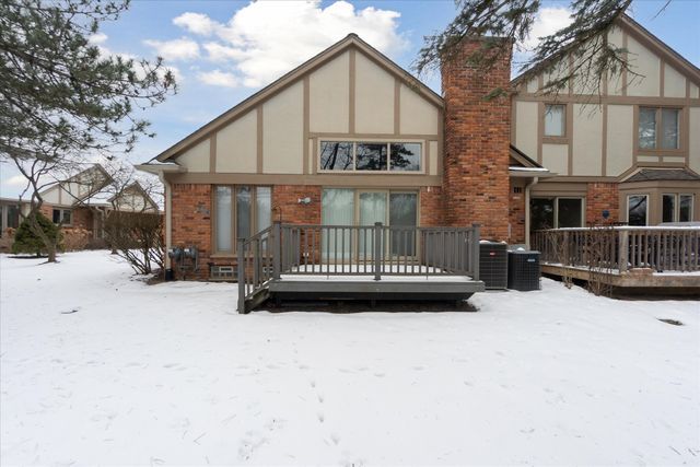 snow covered property with central AC unit and a deck