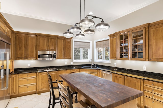 kitchen with a kitchen island, appliances with stainless steel finishes, decorative light fixtures, sink, and ornamental molding