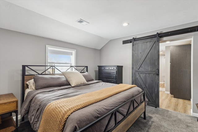 bedroom with a barn door and lofted ceiling