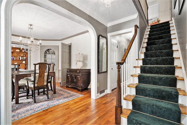 dining room featuring wood-type flooring, crown molding, built in features, and an inviting chandelier