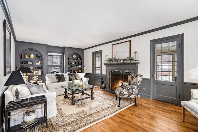 living room with wood-type flooring, built in features, and crown molding