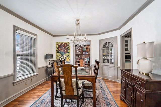 dining room with ornamental molding, a notable chandelier, and light wood-type flooring