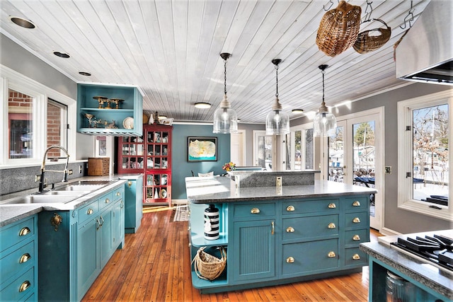 kitchen featuring blue cabinets, decorative light fixtures, light hardwood / wood-style floors, and sink