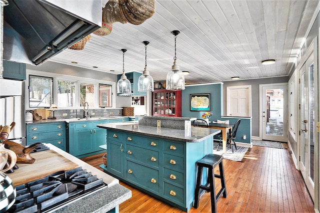 kitchen featuring blue cabinets, a center island, fridge, light hardwood / wood-style floors, and exhaust hood