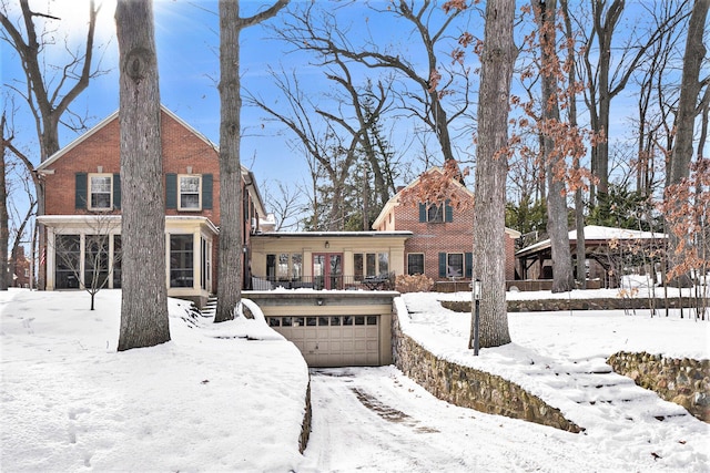 snow covered back of property featuring a garage