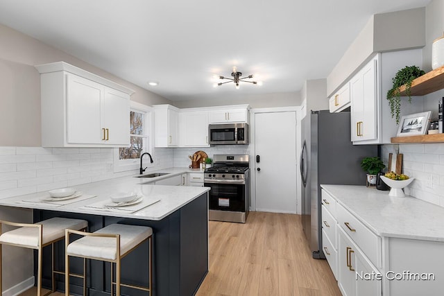 kitchen with sink, backsplash, stainless steel appliances, a kitchen breakfast bar, and white cabinets