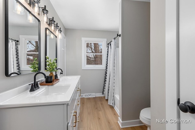 full bathroom with vanity, hardwood / wood-style floors, shower / bath combo, and toilet