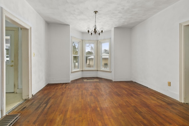 unfurnished dining area featuring a chandelier and dark hardwood / wood-style flooring