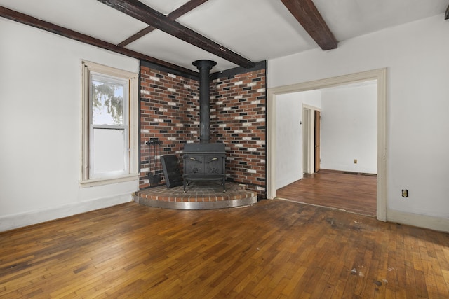 unfurnished living room featuring beamed ceiling, a wood stove, and dark hardwood / wood-style flooring