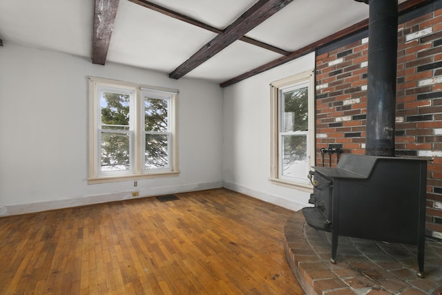 unfurnished living room featuring a wood stove, dark wood-type flooring, and beam ceiling