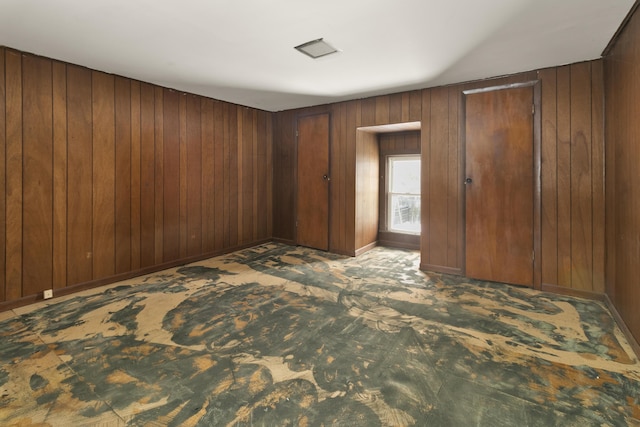 unfurnished bedroom with dark colored carpet and wood walls