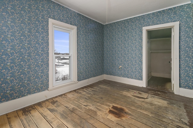 unfurnished bedroom with multiple windows, hardwood / wood-style floors, crown molding, and a closet