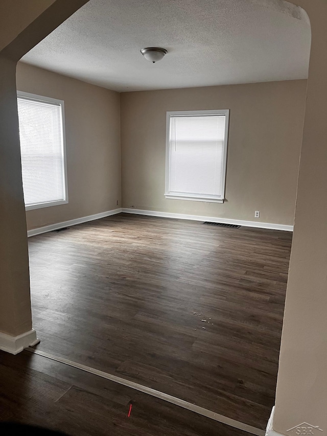 spare room featuring dark hardwood / wood-style floors and a textured ceiling