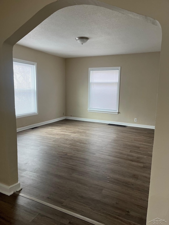 empty room featuring dark hardwood / wood-style floors and a textured ceiling