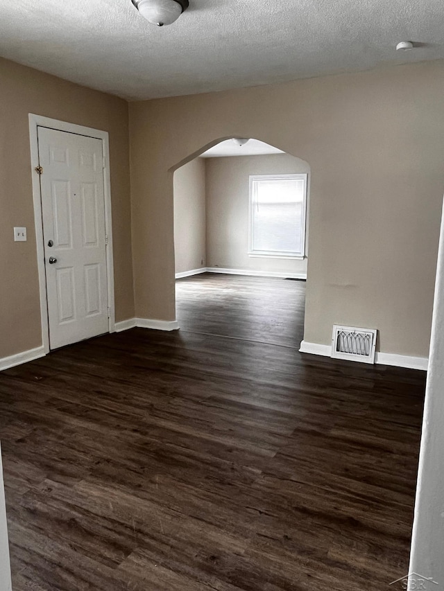 empty room with a textured ceiling and dark hardwood / wood-style flooring