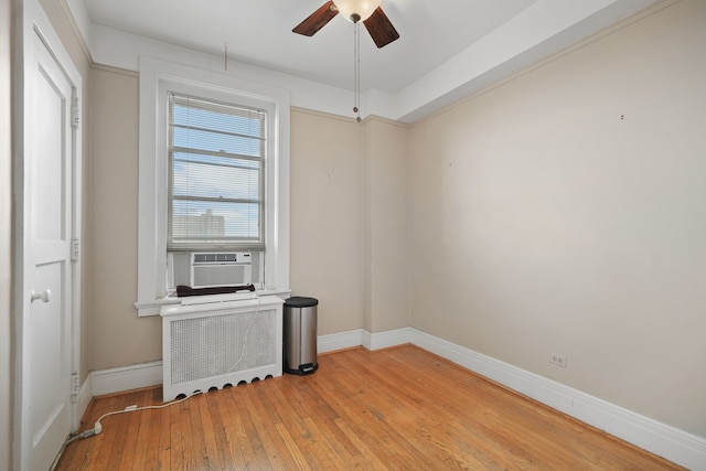 empty room featuring radiator, cooling unit, ceiling fan, and light hardwood / wood-style flooring