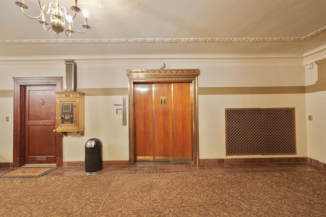 corridor featuring elevator, ornamental molding, and a notable chandelier