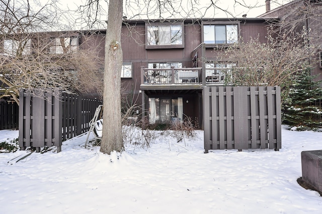 snow covered rear of property with fence