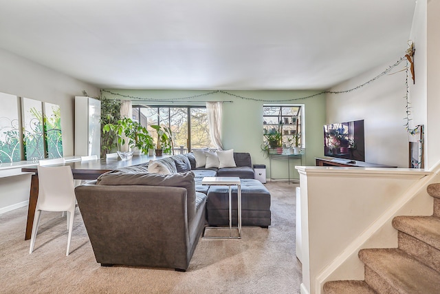 living area featuring light carpet, stairs, and baseboards